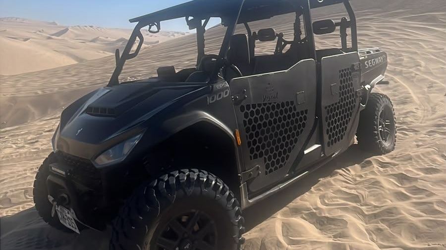 Black factory-built UTV with a roll cage parked on a Huacachina dune